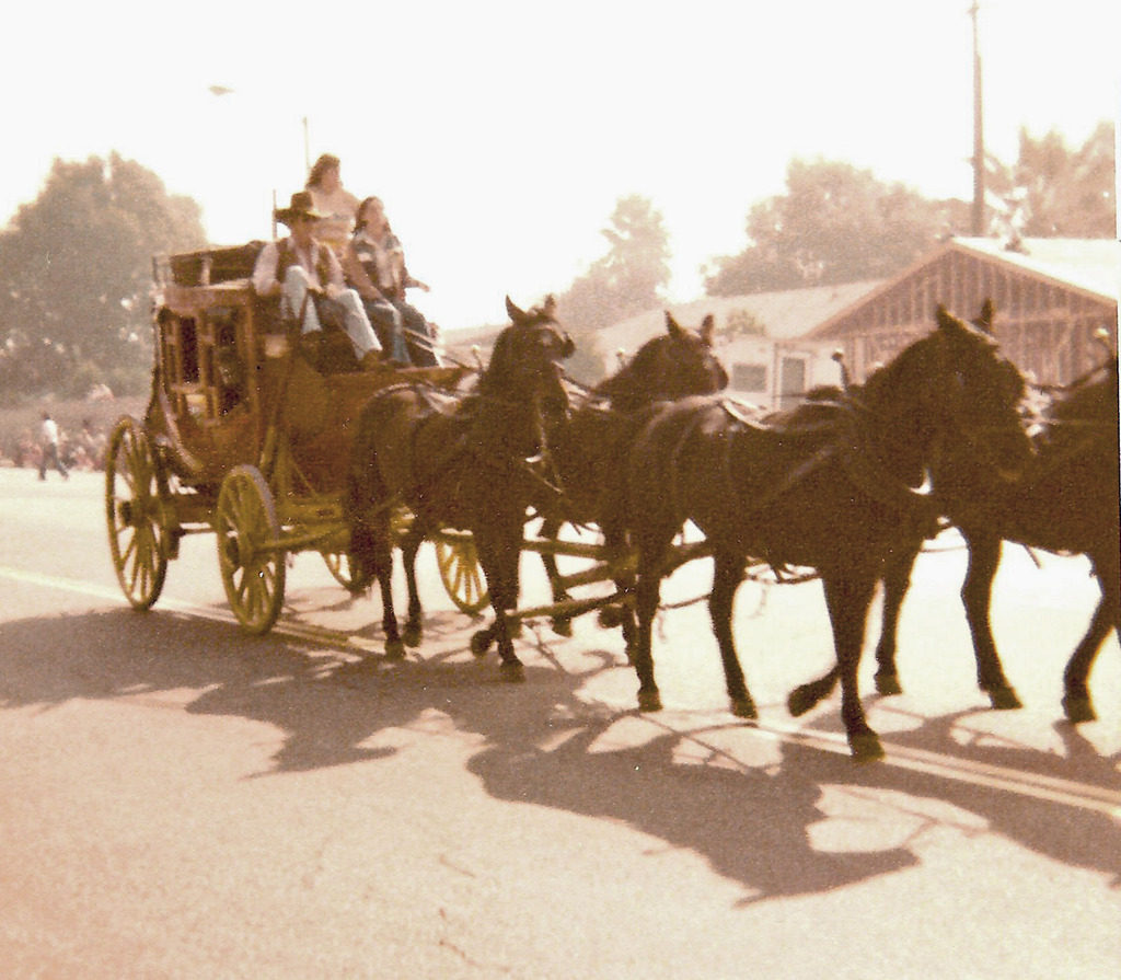 An old image of a family in a carriage pulled by horses