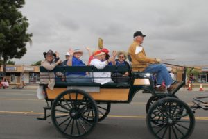 Elderly people waving from their carriage