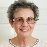 A headshot portrait of a woman with glasses